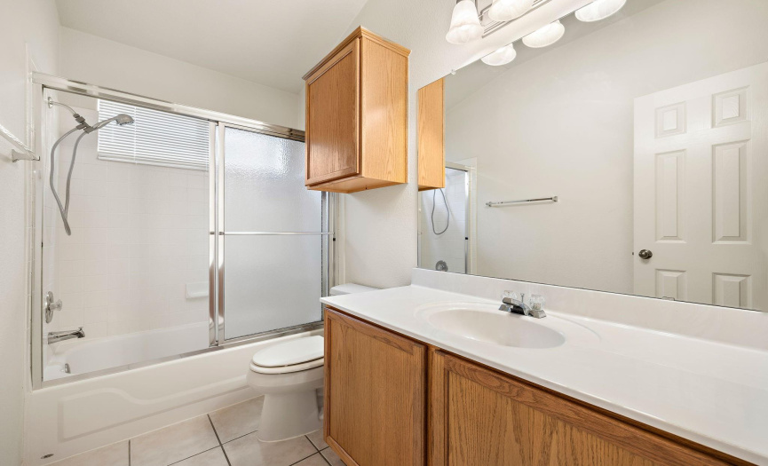 Guest Bathroom with extra cabinets, lots of counter space, a glass sliding door, and a window for natural light.