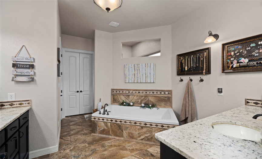 The primary bathroom includes a soaking tub, separated vanities, and a luxuriously large walk-in shower. The spacious closet features custom built-in storage solutions.