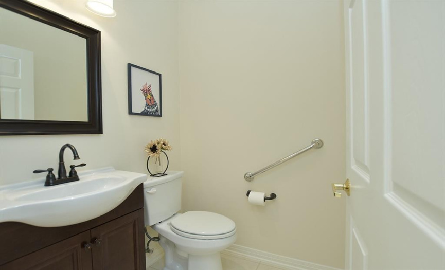 Well placed between living/dining and kitchen/family room, a charming powder room includes recent  vanity/faucet/light fixture with coordinating mirror.
