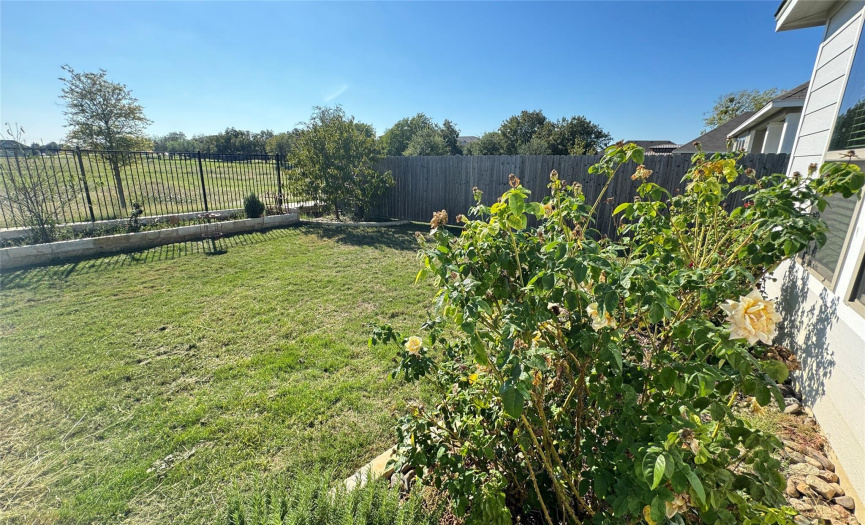 Landscaped backyard with wrought iron fencing showing walking trail...makes your yard feel huge.