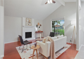 Entering the home, you're greeted by a spacious living room with a vaulted ceiling and cozy fireplace.