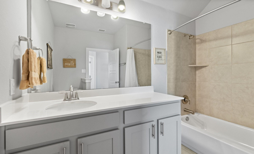 The shared guest bath features modern amenities and a tasteful design, catering to the needs of family and guests.