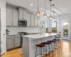 The kitchen shines with beautiful pendant lighting, an arabesque tile backsplash, and sleek quartz countertops. 
