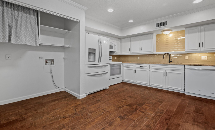 The spacious kitchen features sleek granite countertops, Whirlpool appliances, and tile backsplash.