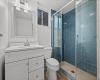 Just outside the primary bedroom you will find this tastefully updated full bathroom with a chic vanity and lovely walk-in shower with blue subway tile surround and sliding glass doors. 