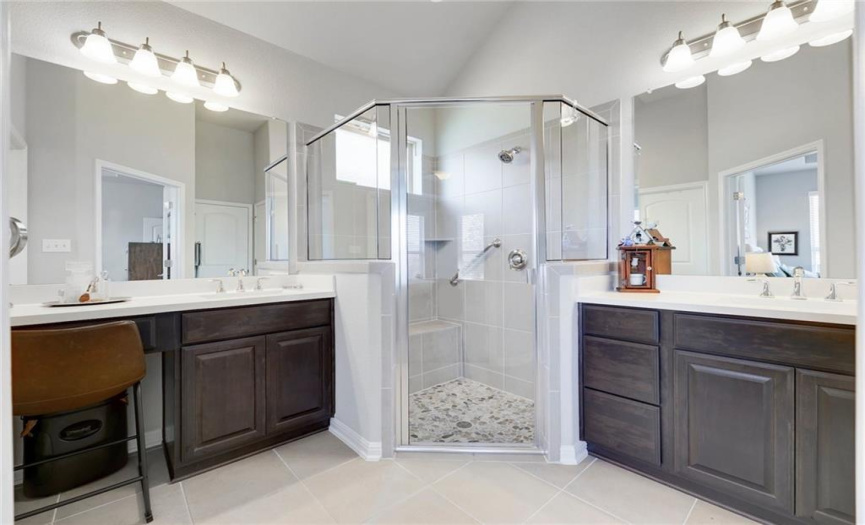 Spa-like primary bathroom. Two vanities and spacious walk-in shower with seat and bar.