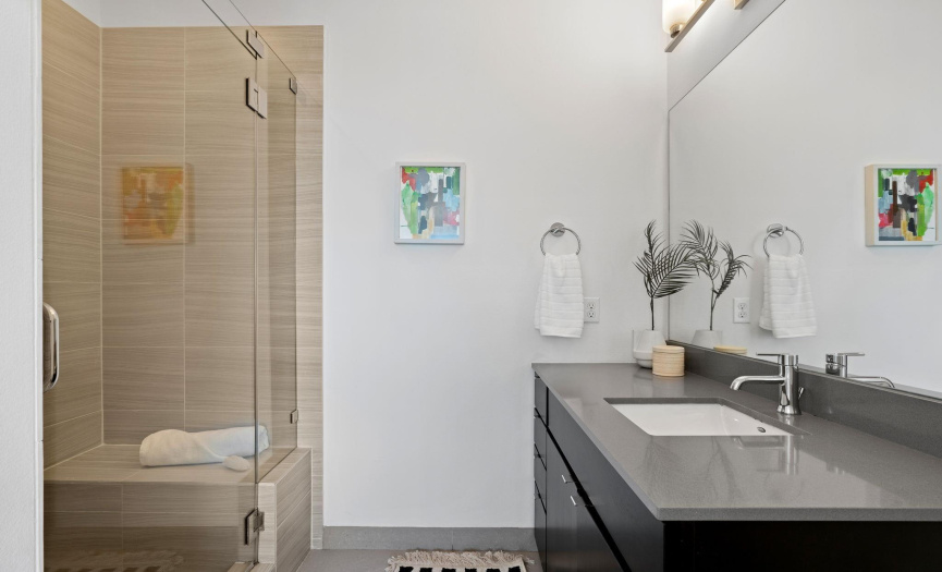 Enjoy your own spa-like private ensuite bath with custom contemporary cabinetry, quartz countertops, and a dreamy frameless glass walk-in shower with tasteful tile surround. 