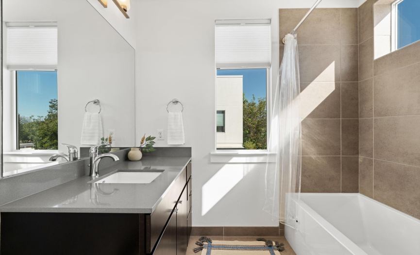 Gorgeous third floor secondary bathroom with a stylish contemporary quartz vanity, modern shower/bath combo, and beautiful tile flooring and backsplash. 