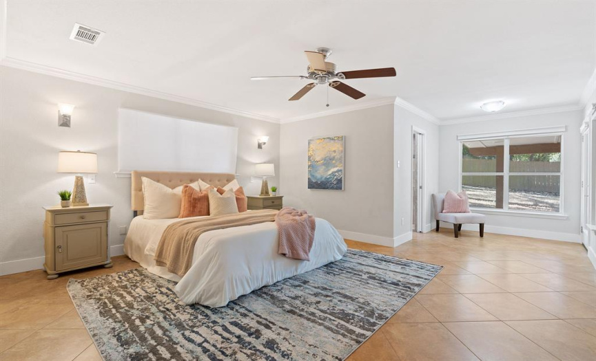 Primary bedroom offers a spacious walk-in closet, ceiling fan, and convenient access to the screened-in porch for a seamless blend of comfort and outdoor charm.