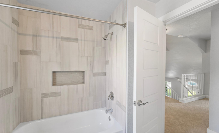 Gorgeous designer tile backsplash lines the shower/tub combo. 