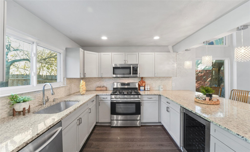 The stylishly updated kitchen serves as the heart of the home and features sleek quartz countertops, SS appliances, a wine fridge, and timeless Shaker-style cabinetry. 