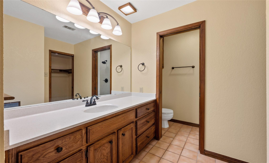Primary bath with private toilet room, long counter and cupboards, walk in closet.
