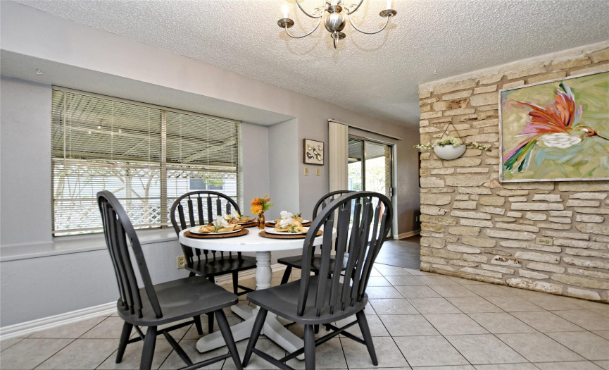 The timelessly stylish stone masonry wall provides a gorgeous backdrop along the dining area, which connects seamlessly to the living room. 
