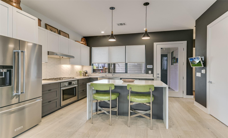 The kitchen offers a convenient breakfast bar/center island, a pantry, high ceilings, and charming light fixtures.
