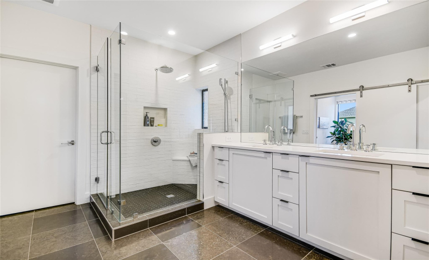 Tile flooring, dual vanities, bright lighting, and a gorgeous walk-in shower.