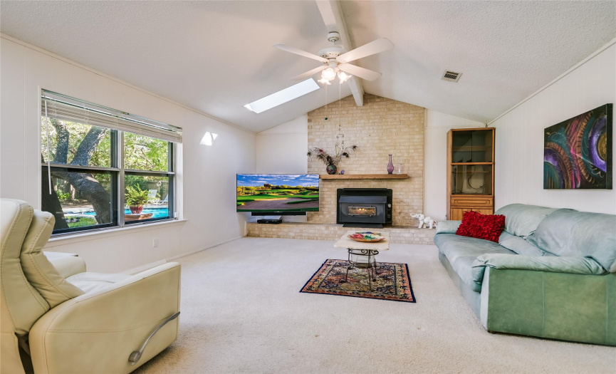 High cathedral ceilings, skylights, a ceiling fan, and a welcoming wood-burning fireplace in the spacious family room, connected to the kitchen.