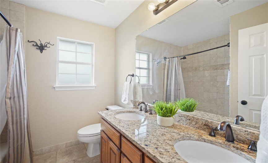 Secondary bathroom with dual vanities, granite countertops and oil-rubbed bronze fixtures.