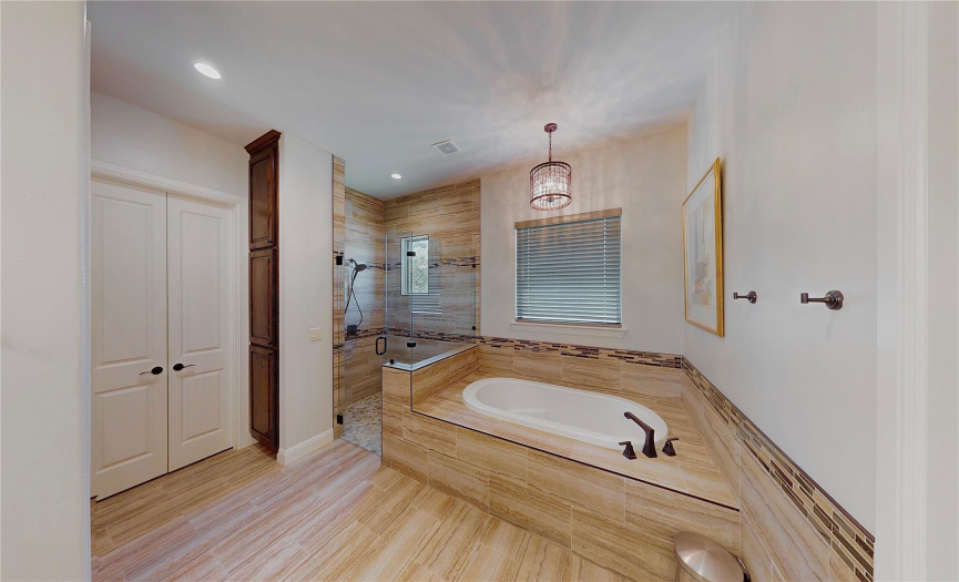 Relaxing soaking tub and large walk-in frameless shower. Note the chandelier!