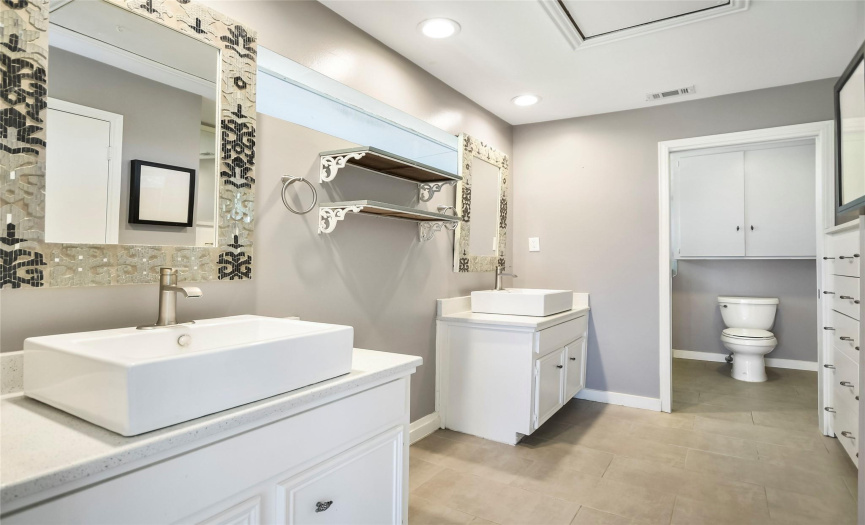 Primary bathroom features 2 vanities, built-in dressers, and walk-in frameless shower and walk-in closet.