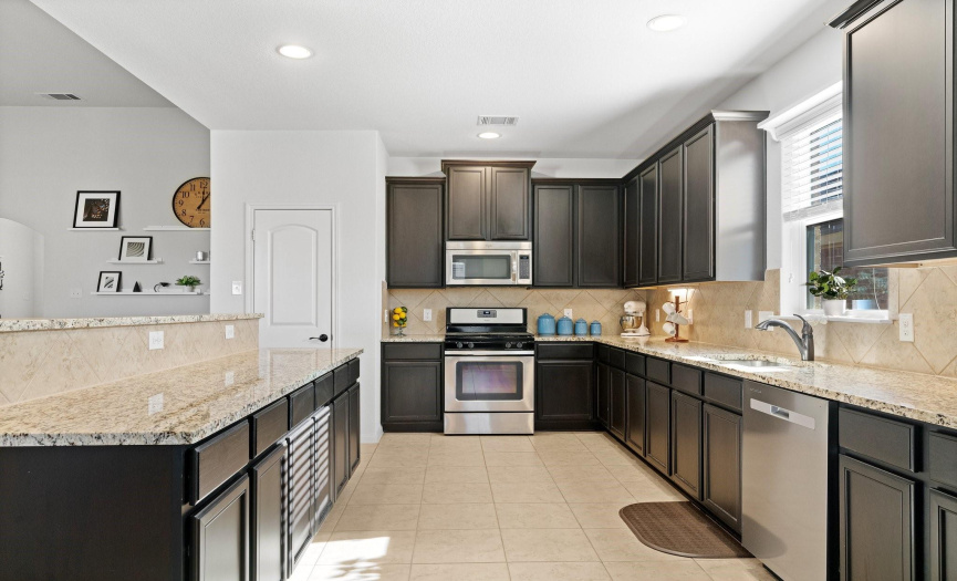 Other notable features in the kitchen include undercabinet lighting, a tile backsplash, and an undermount stainless-steel sink.