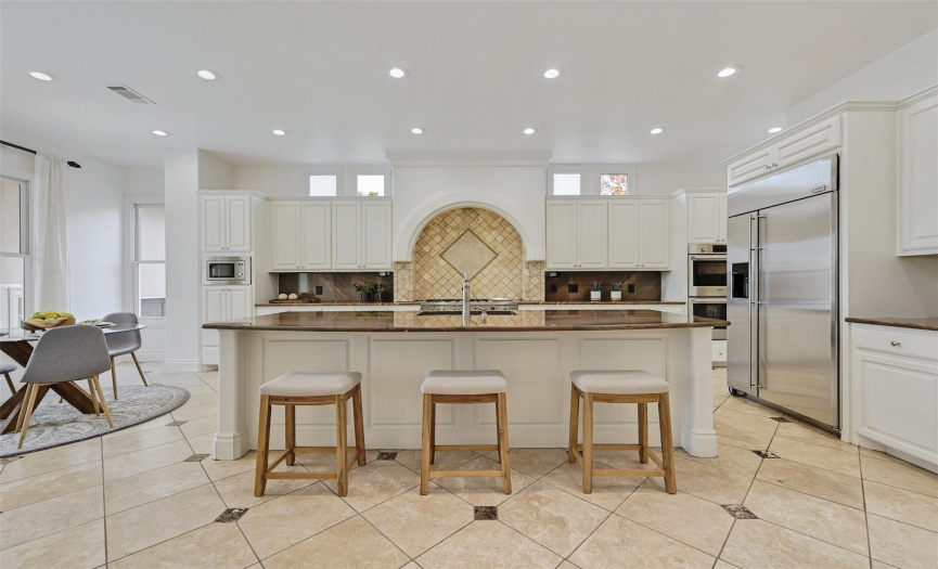 Chef’s kitchen with oversized granite island, two dishwashers, Bertazzoni 6 burner gas cooktop with integrated griddle, dual ovens, counter height seating and light-filled breakfast nook.