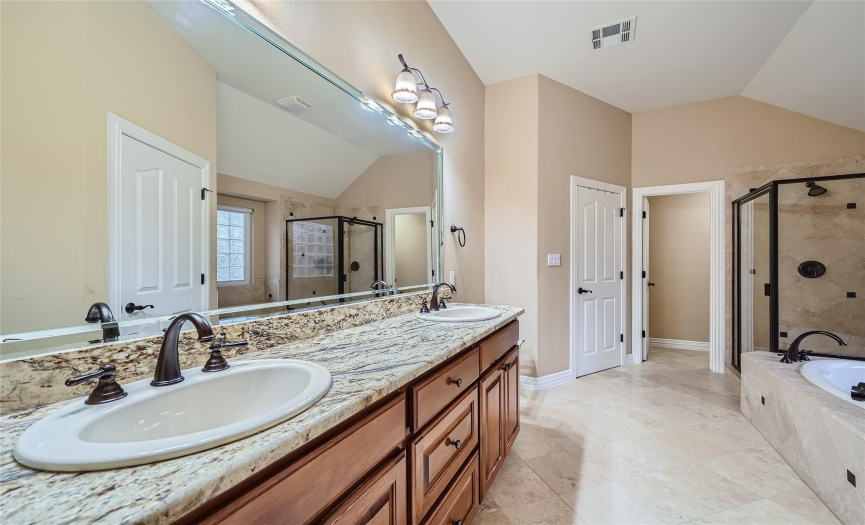 primary bathroom with double vanities , separate walk in shower, jetted tub and two walk-in closets