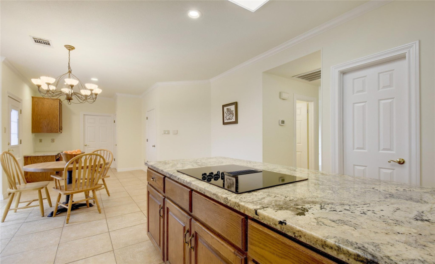 Kitchen area with stylish granite counters, eat in option, kitchen island adding more work areas and counter space with cook top, cupboards and cabinets.  Work desk, office area desk back by utility room.