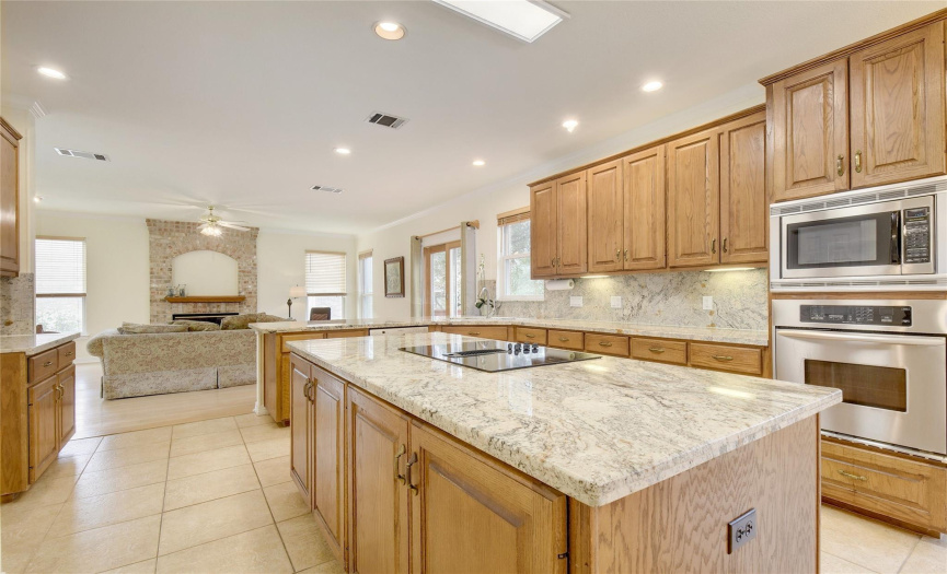 Great shot of kitchen area with granite counters, corner sink, breakfast bar, tile flooring, multiple lights, under counter accent lighting, bright and warm features.