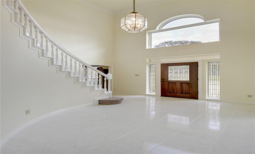 Gorgeous entry foyer with dramatic front windows, high ceiling, chandelier, white file flooring, sweeping entry staircase.