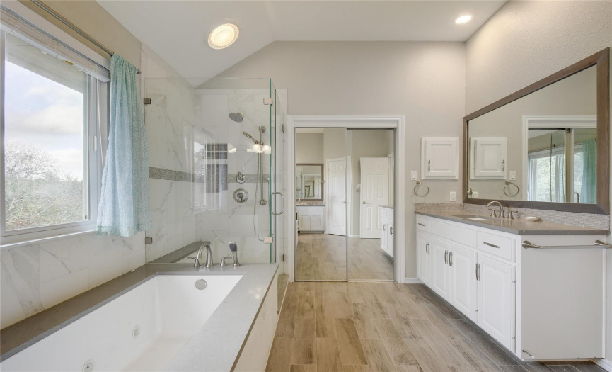 Primary bath with soaker tub, separate shower, tile flooring, window, lighting.