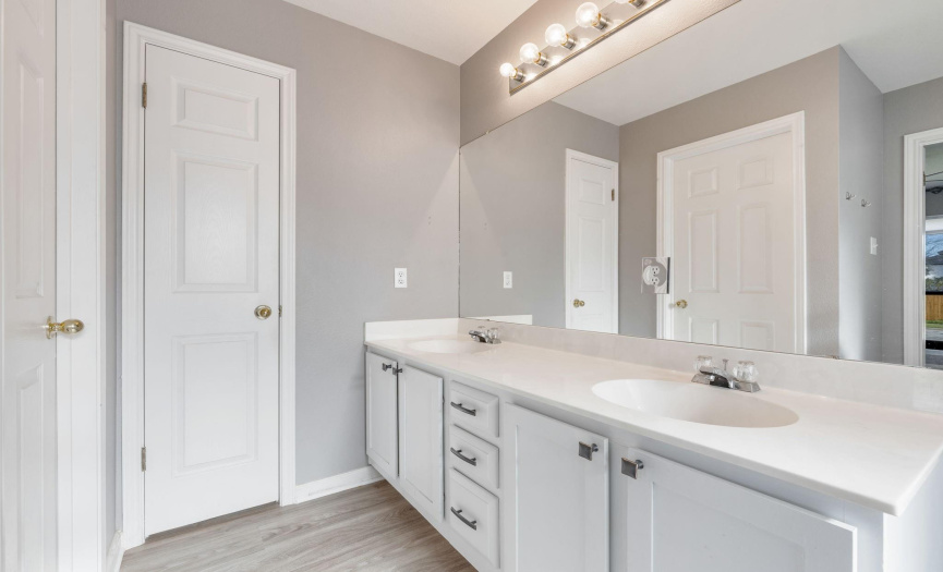Master bathroom has a double vanity,  painted cabinets with hardware, linen closet, separate shower, garden tub, water closet, and vinyl plank flooring.