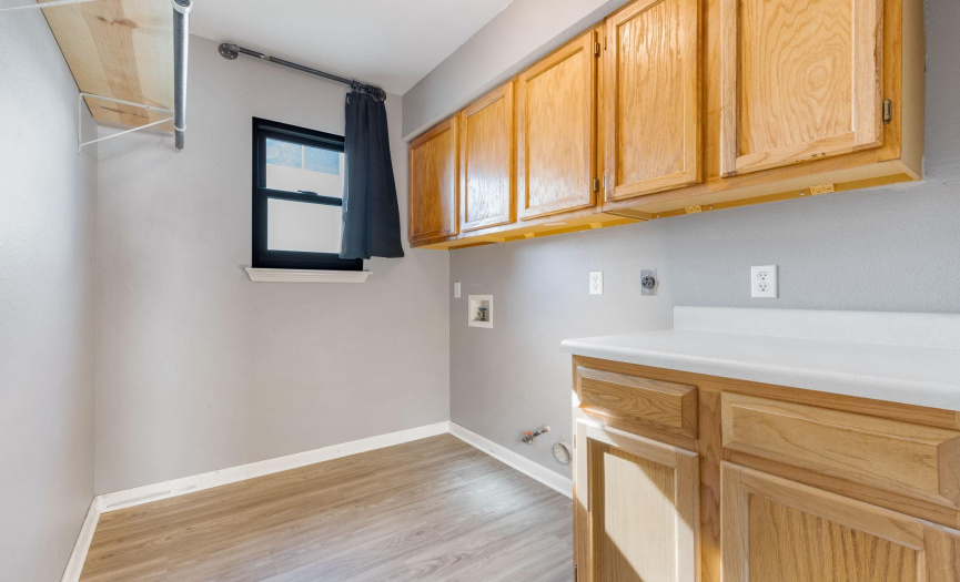 Laundry room has counter space, both gas and electric connections for the dryer, and vinyl plank flooring.