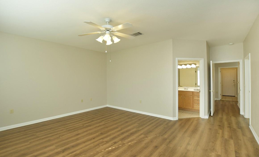 The same flooring continues into the primary bedroom along with the same neutral color wall paint.