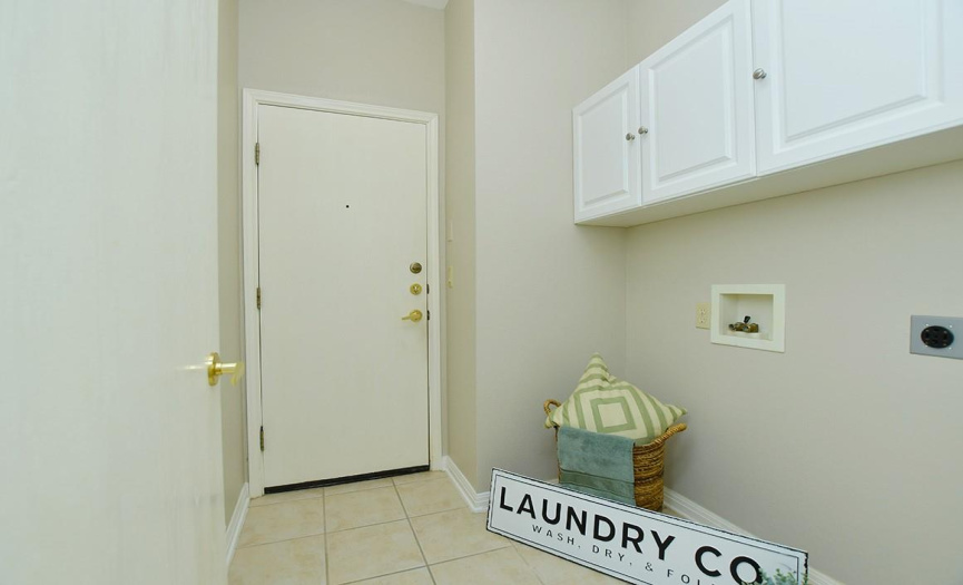 The utility room features closed overhead storage and is located on the way into the garage.