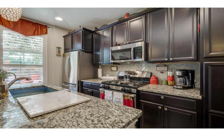 The kitchen boasts stainless steel appliances including a gas oven/range.