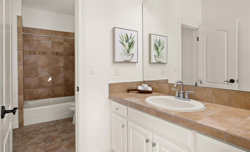 The vanity area for the secondary bedroom offers access to the shared Jack-n-Jill water closet with the shower/tub combo and commode. 