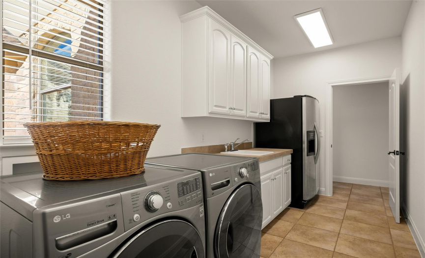 The large in home laundry room provides plentiful storage cabinetry and a vanity with a sink, plus space fro a full second fridge. 