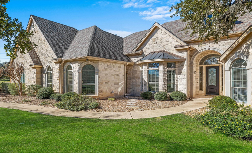 Featuring lush professional landscaping, majestic shade trees, striking Austin stone masonry, and a side-facing, three-car garage. 