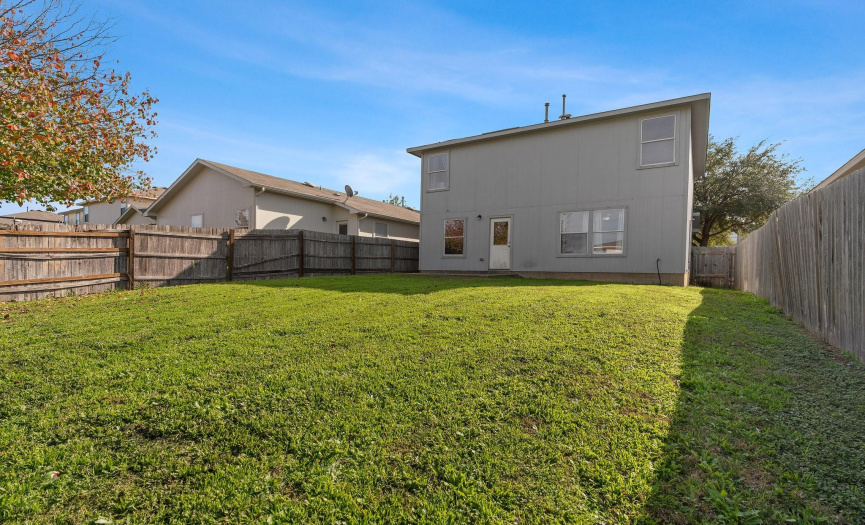 The backyard is spacious and enclosed by wood privacy fencing.