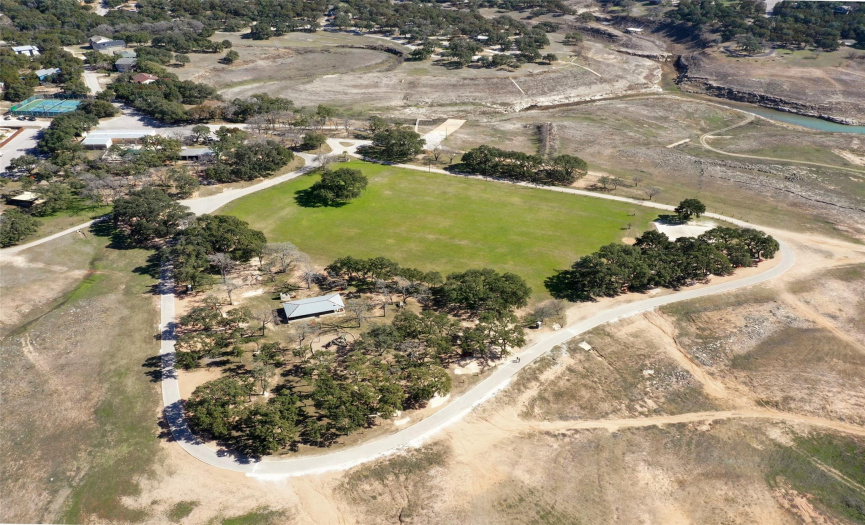 This aerial image is taken in the Bar-K Ranch Park. You can see the baseball field, the playground area, tennis courts, a community pavilion, volleyball court and the cove that still has some water remaining which extends toward the lot.