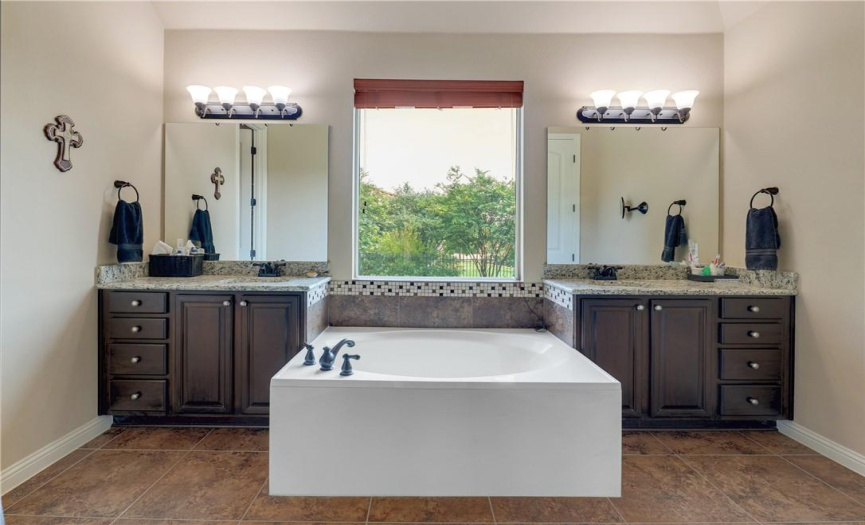 Master bath features walk-in glass shower, two vanities, and a soaking tub