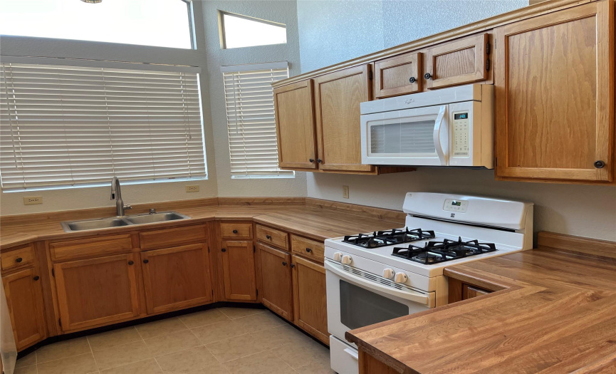 Kitchen with gas stove & microwave oven & plenty of cabinetry & counter space.