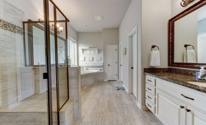 Immerse yourself in the ultimate relaxation in the ensuite bath with separate vanities, a jetted tub, and a spacious walk-in closet
