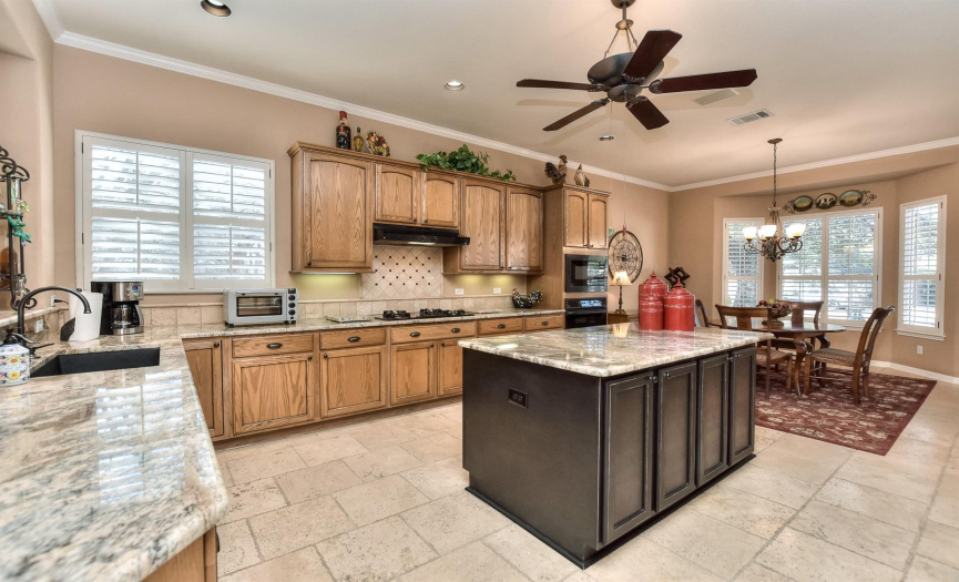 Plenty of space in this island kitchen with natural wood cabinetry and Travertine tile flooring