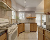  The kitchen is a chef's delight, offering ample cabinetry for storage, tiled countertops, and high-quality appliances. 