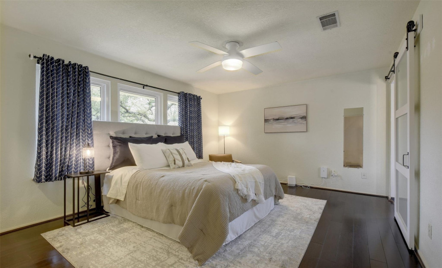 Retreat to the serene primary bedroom featuring hardwood flooring, a walk-in closet, and a private en-suite bath enclosed by a charming barn door.