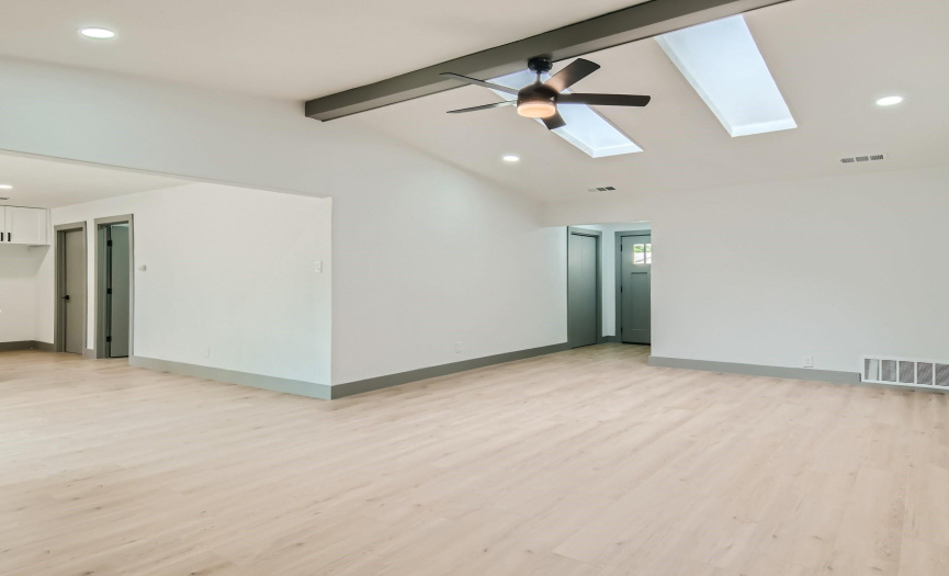 Showcasing the skylights in the family room, vaulted ceiling, new LVP flooring and open to kitchen on left.