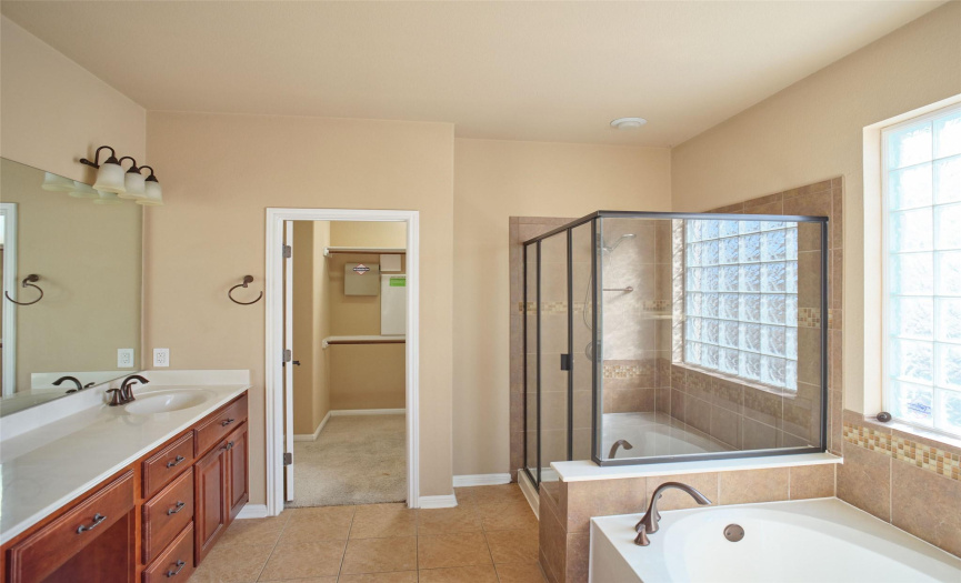 The primary bath has a separate shower, soaking tub, single sink with a vanity, and a walk in closet.