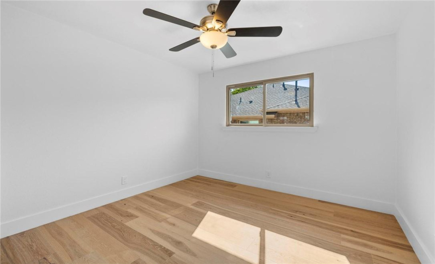 The fourth bedroom is also big with wood flooring, a ceiling fan, and natural light.
