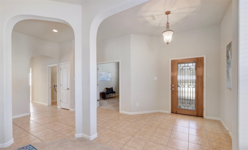 Lovely archways looking into the front foyer and a peak into the bonus room to the left. Guest rooms down the hall, separate from the primary bedroom. 